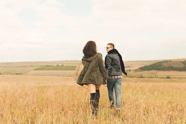 A couple walking together through a sunlit field